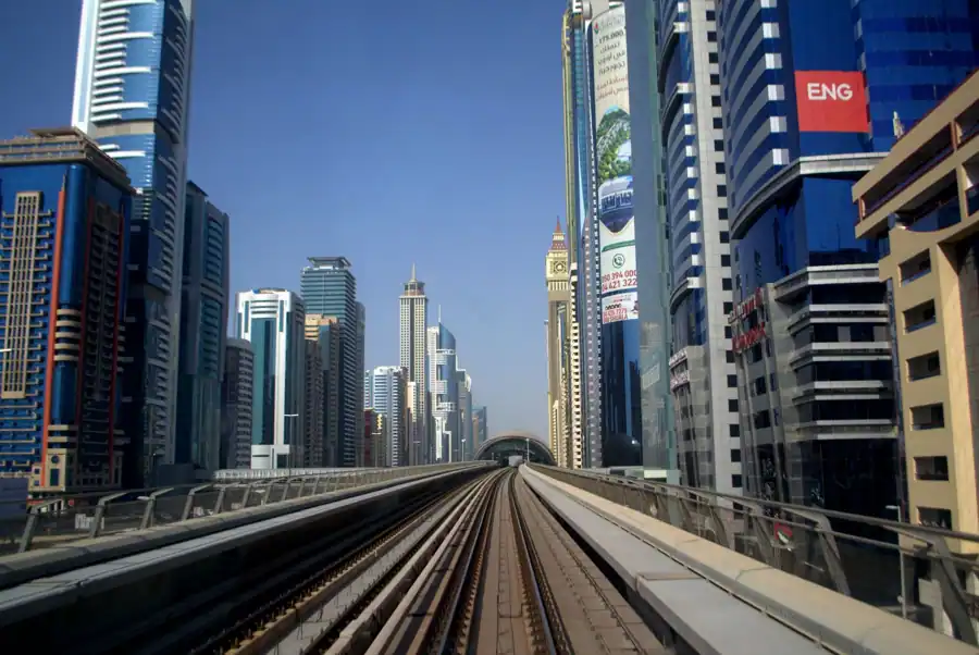 Dynamic shot of Dubai Metro with futuristic skyline in the background, showcasing urban transportation and architecture.