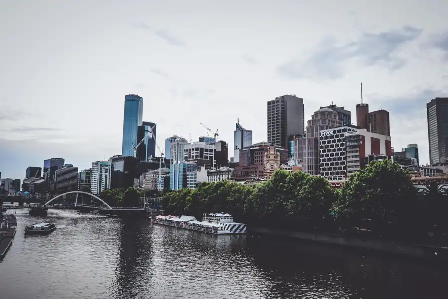 View of Melbourne's skyline with skyscrapers reflecting along the Yarra River, showcasing urban architecture.